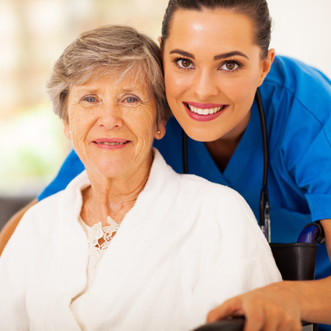 happy senior woman on wheelchair with caregiver