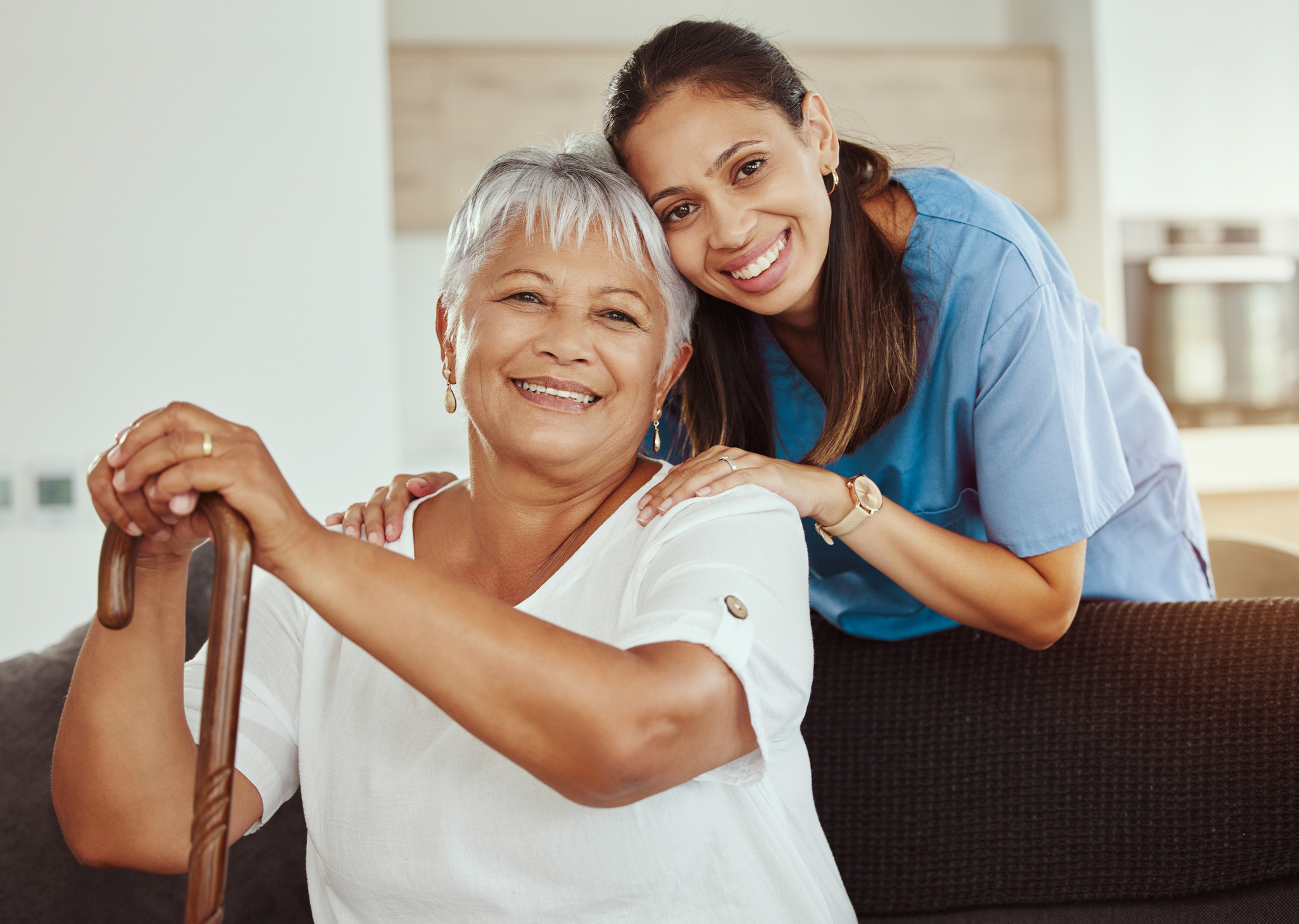 Compassionate Home Care That Feels Like Family Caregiver hugging an elderly woman with a cane after a comforting walk outdoors.
