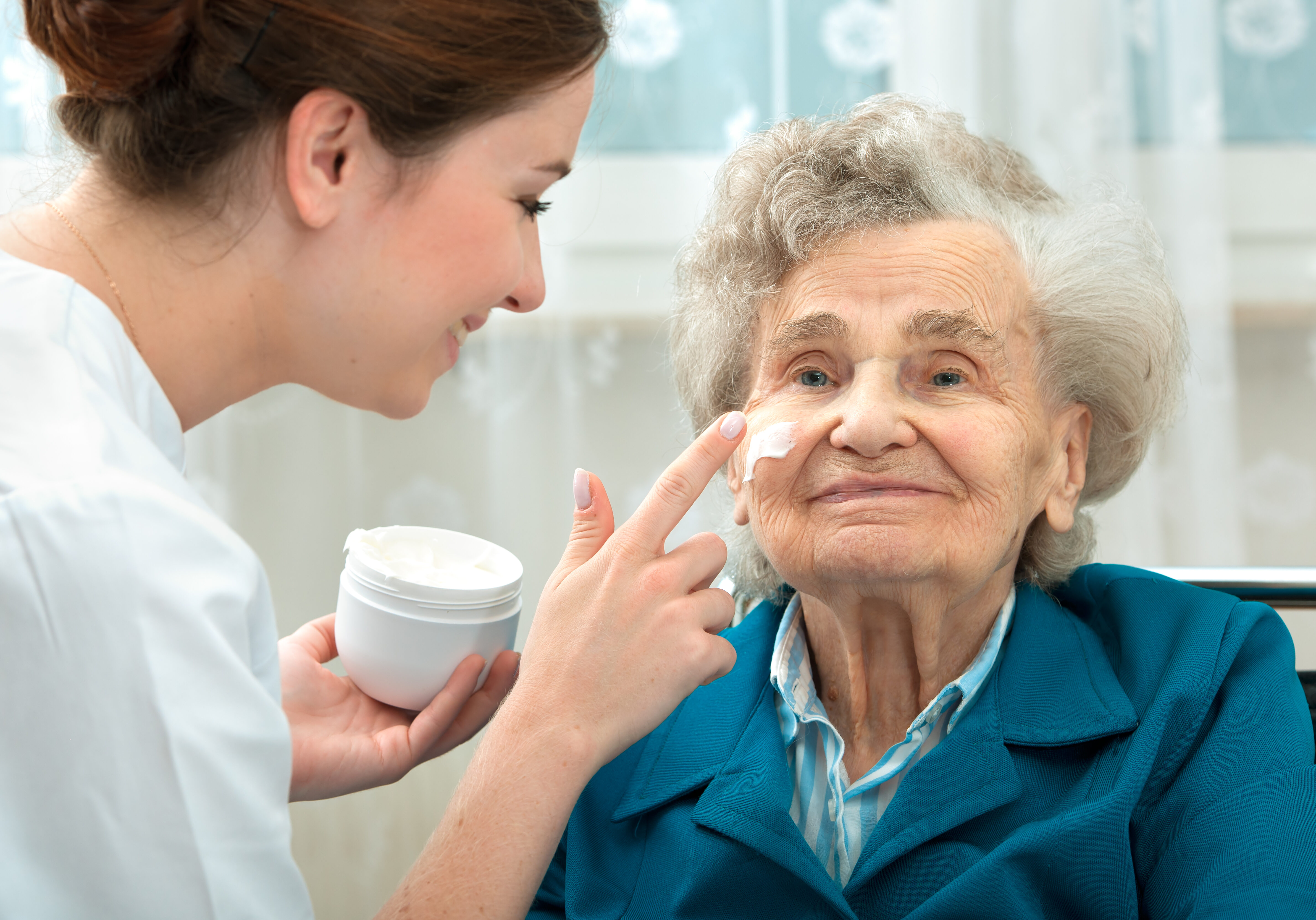 Nurse assists an elderly woman with skin care and hygiene measures at home